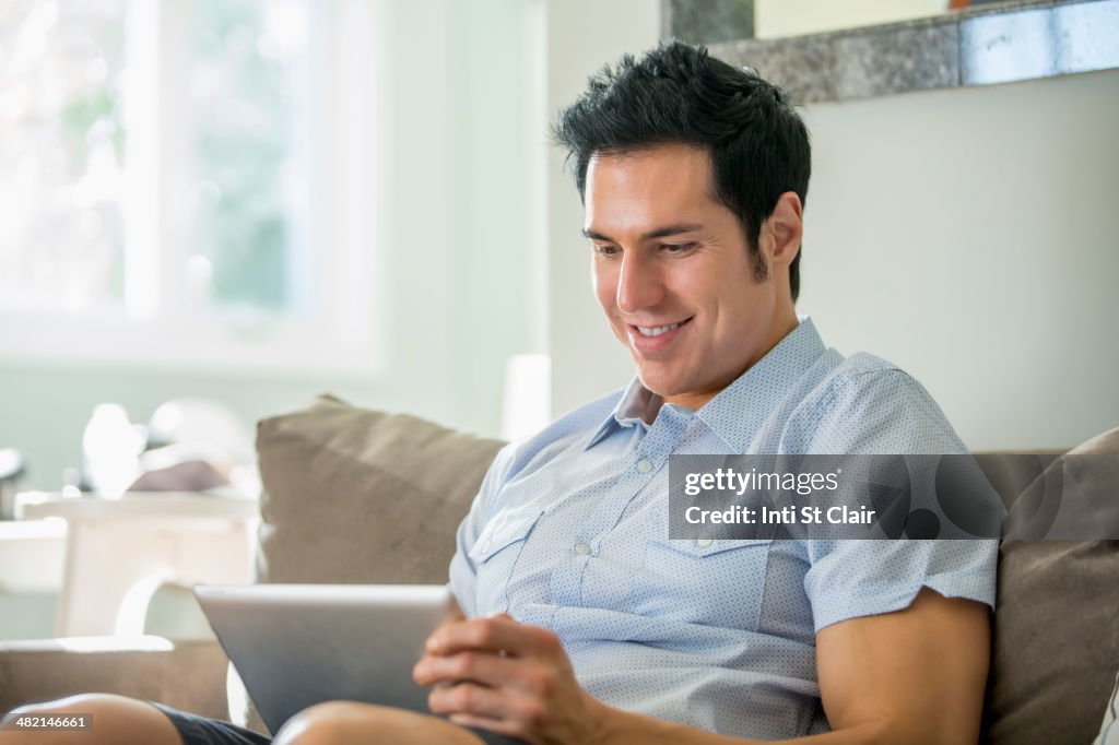 Caucasian man using digital tablet on sofa