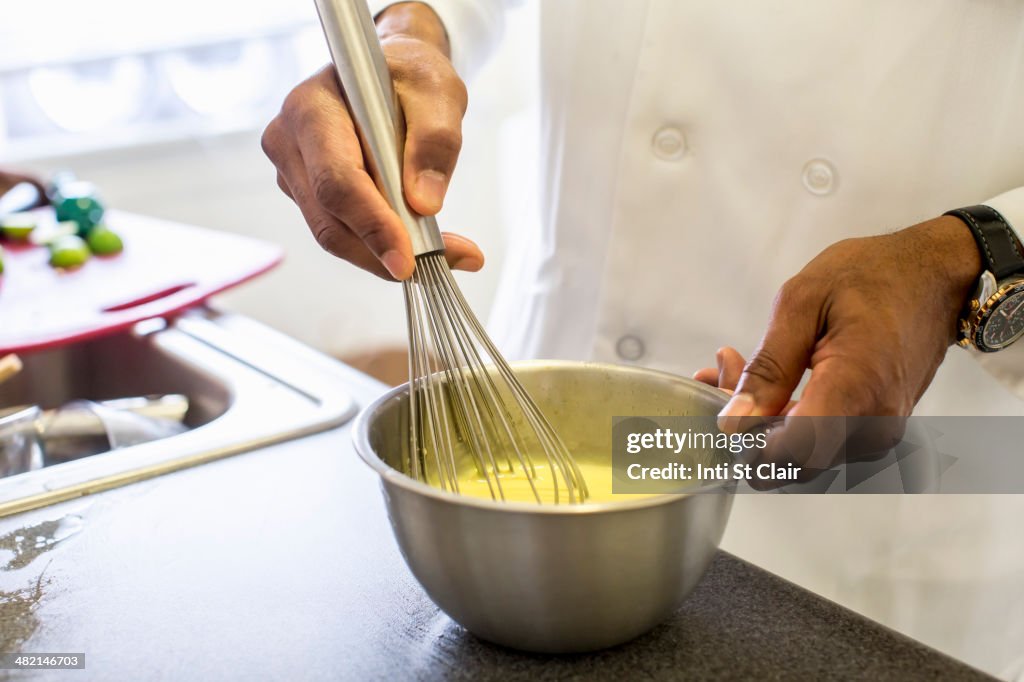 Black chef whisking eggs in restaurant