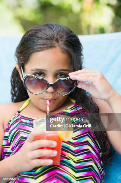 mixed race girl sipping juice at poolside - diva human role stockfoto's en -beelden