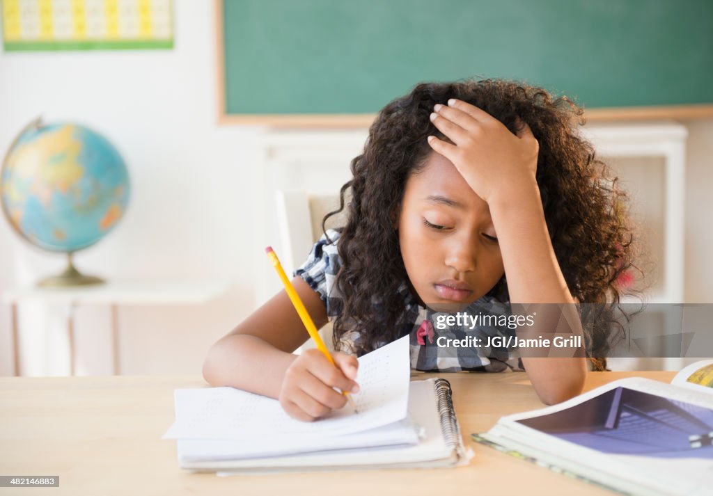 Frustrated mixed race student working in classroom
