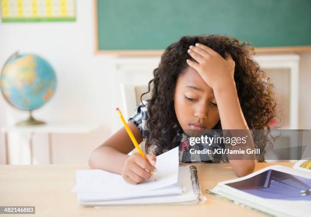 frustrated mixed race student working in classroom - exam desk stockfoto's en -beelden