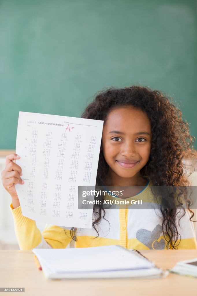 Mixed race student showing off A plus grade in classroom