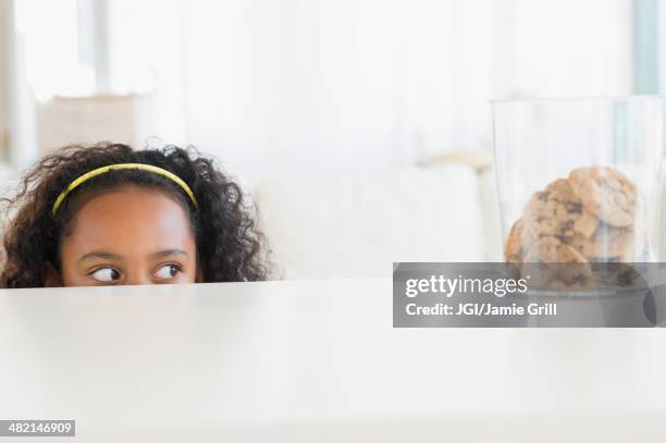 mixed race girl peering at cookie jar - child cookie jar stock pictures, royalty-free photos & images