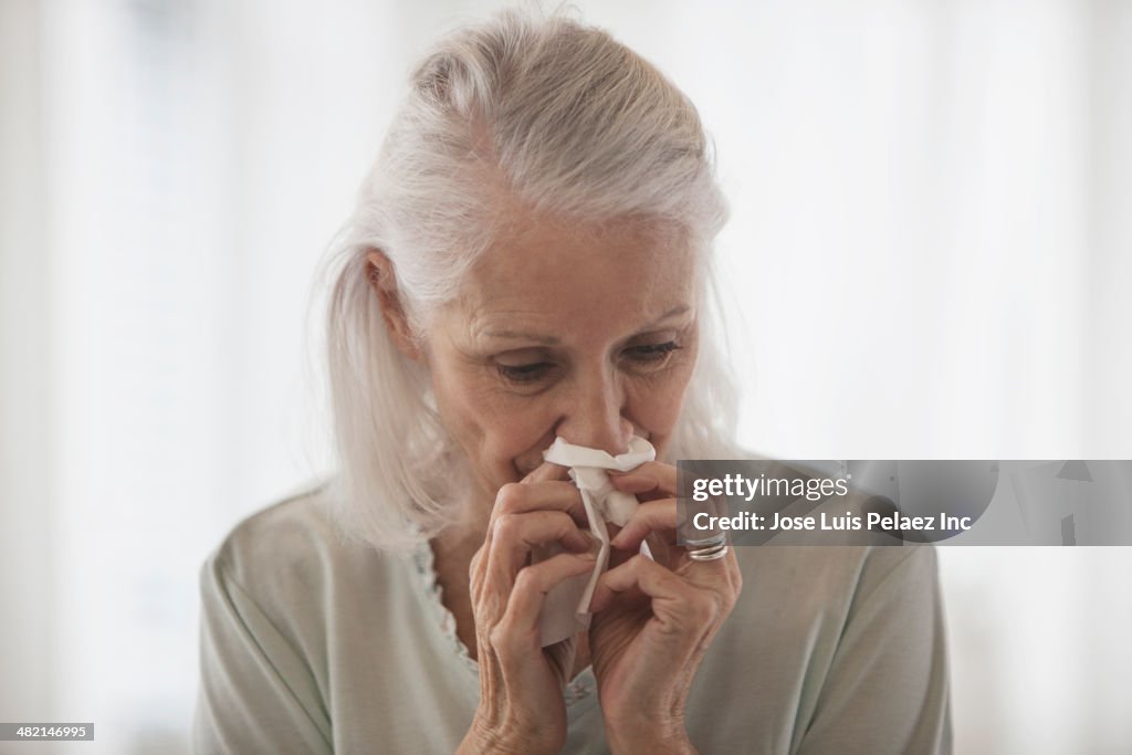 Senior Caucasian woman blowing her nose
