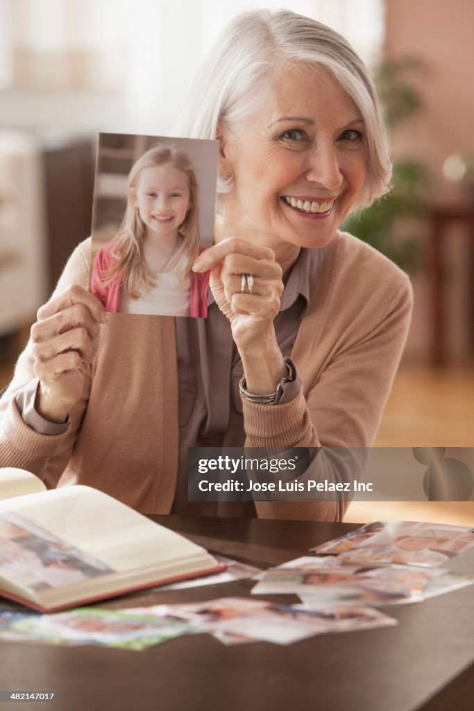 Senior Caucasian woman holding photograph of young girl
