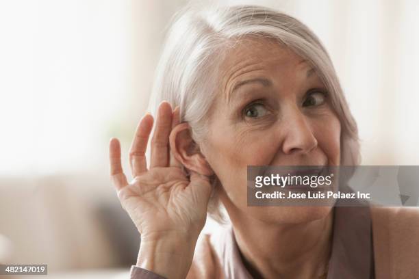 senior caucasian woman cupping her ear to listen - interested listener stock-fotos und bilder