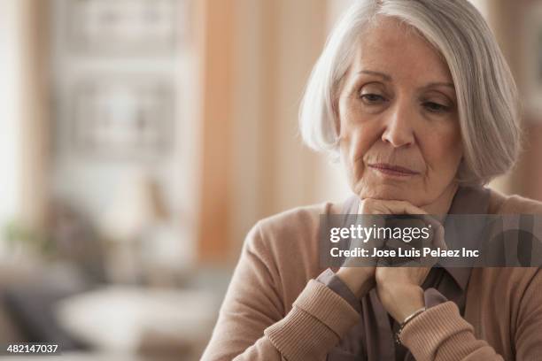 senior caucasian woman with chin in hands - concerned woman stock-fotos und bilder