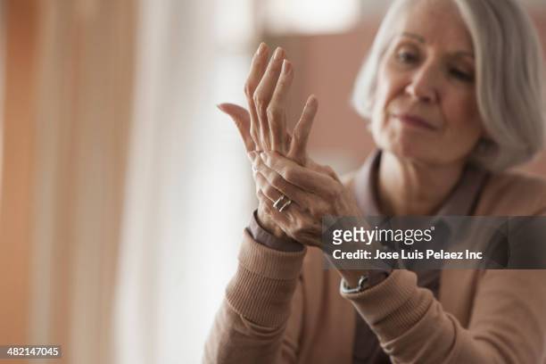 senior caucasian woman rubbing her hands - human body part stock-fotos und bilder