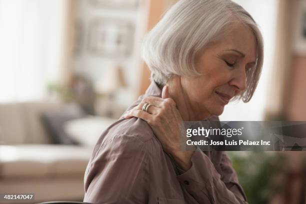 senior caucasian woman rubbing her shoulder - man touching shoulder stock-fotos und bilder
