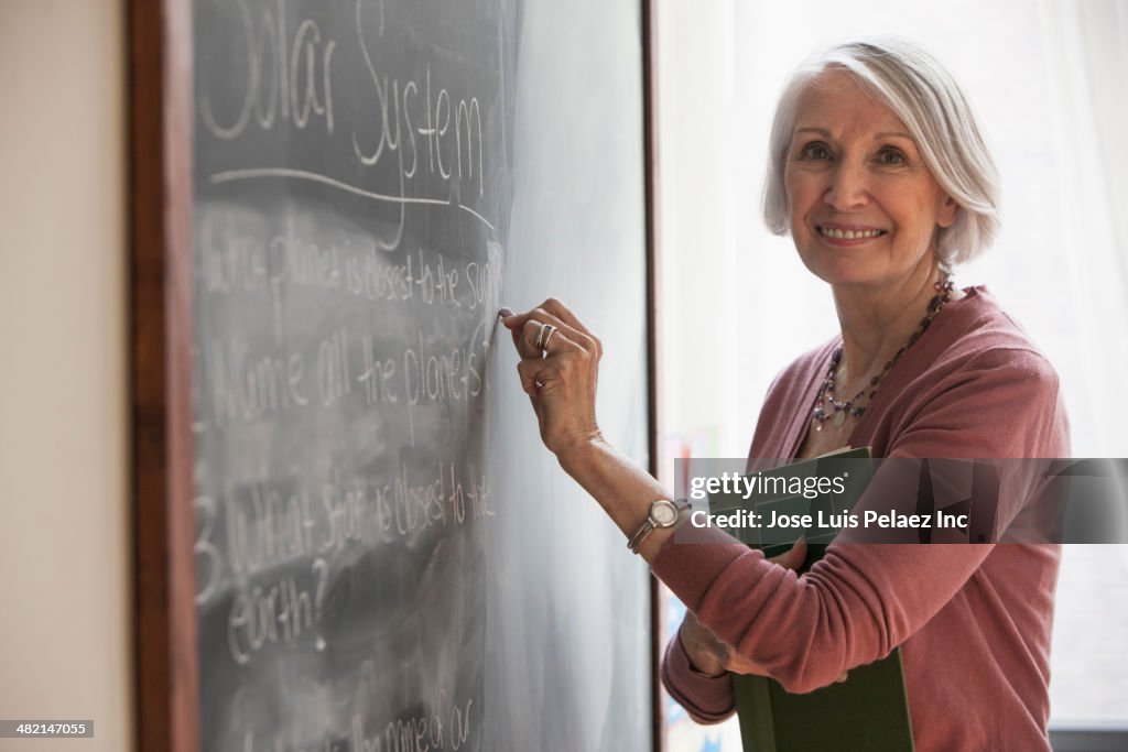 Caucasian teacher writing on chalkboard