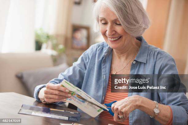 senior caucasian woman clipping coupons - frugalidad fotografías e imágenes de stock
