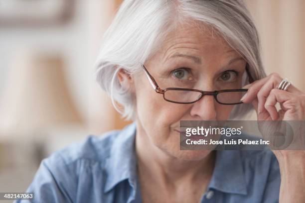 senior caucasian woman peering over her eyeglasses - suspicion stock pictures, royalty-free photos & images