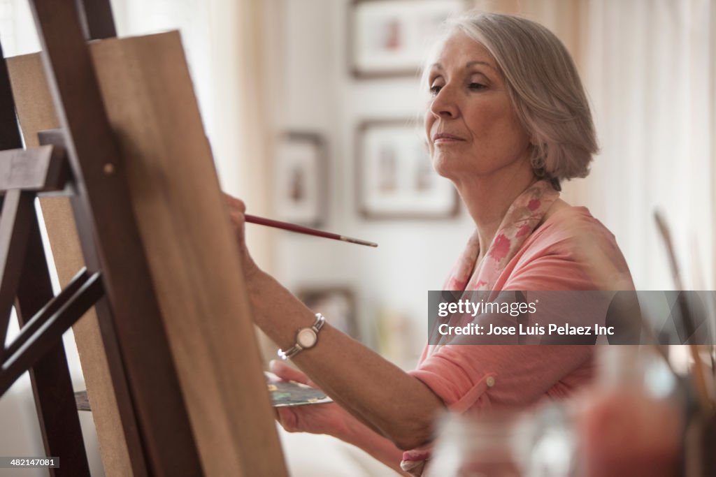 Senior Caucasian woman painting at easel