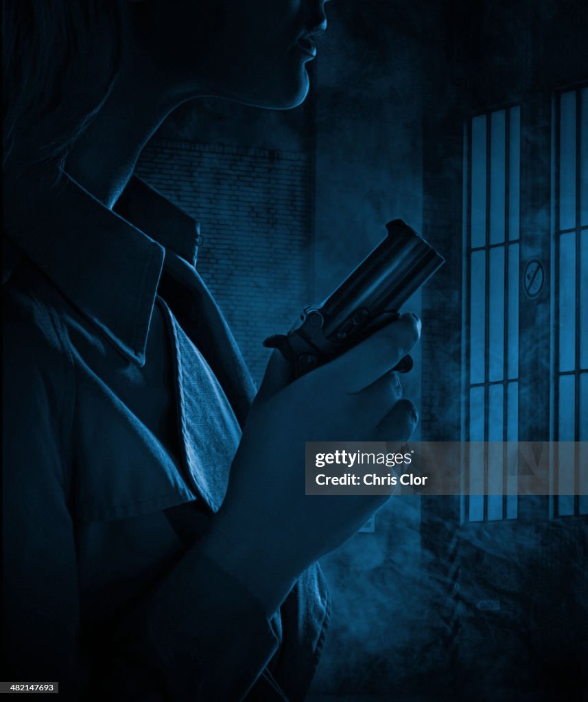Silhouette of woman holding gun in dark room