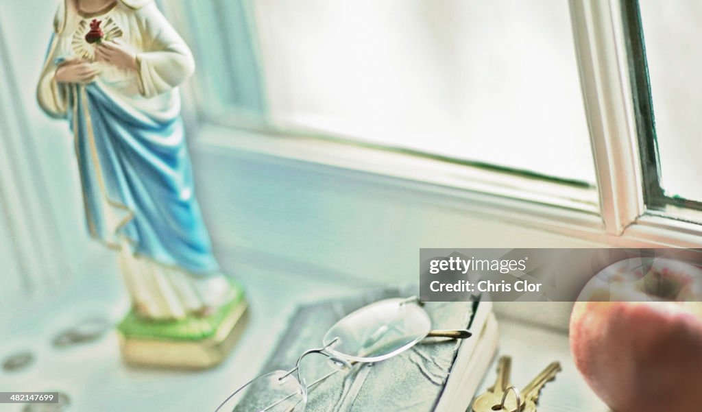 Close up of glasses, religious statue and fruit on windowsill