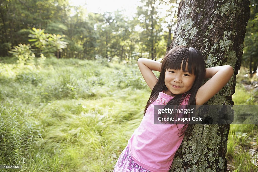 Girl leaning against tree outdoors