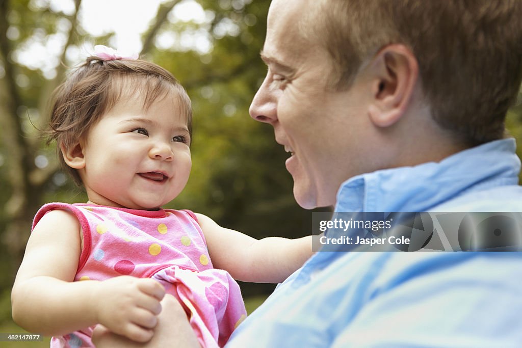 Father holding baby girl in park