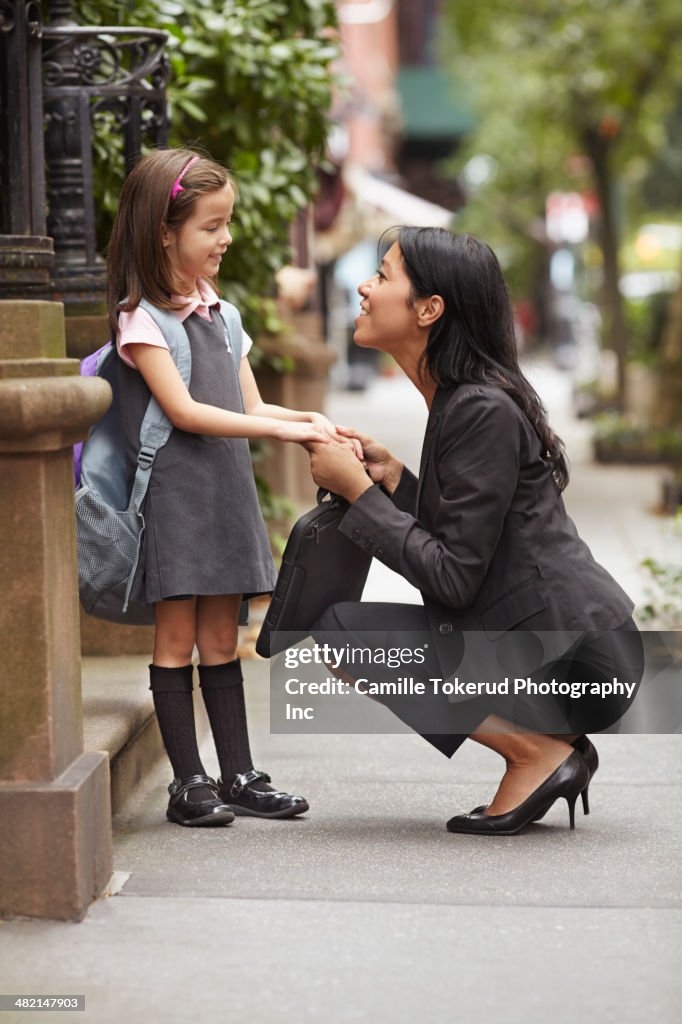 Mother greeting daughter on city street