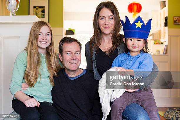 family smiling together in living room - adopted chinese daughter stock pictures, royalty-free photos & images