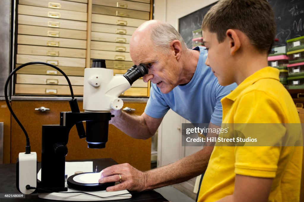 Teacher and student using microscope in laboratory