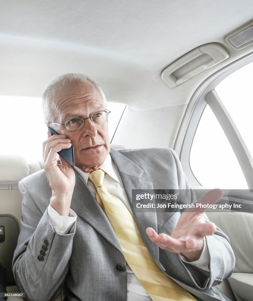 Caucasian businessman talking on cell phone in car