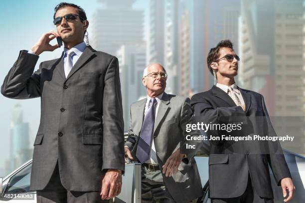 bodyguards protecting businessman on city street - 警護する ストックフォトと画像