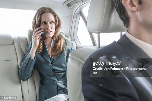 businesswoman talking on cell phone in car - chauffeur stock pictures, royalty-free photos & images