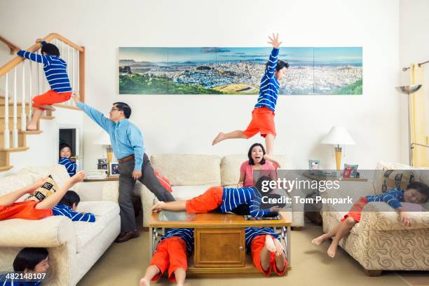 chinese parents watching son climb all over house - stressed young woman sitting on couch stock-fotos und bilder