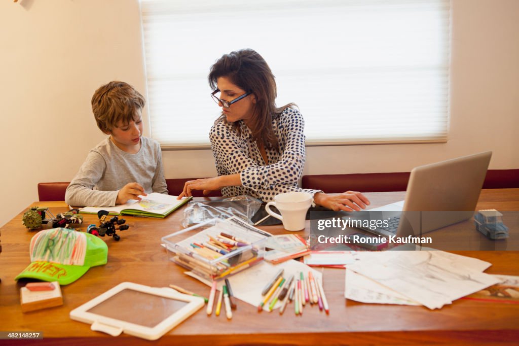 Caucasian mother and son working at table
