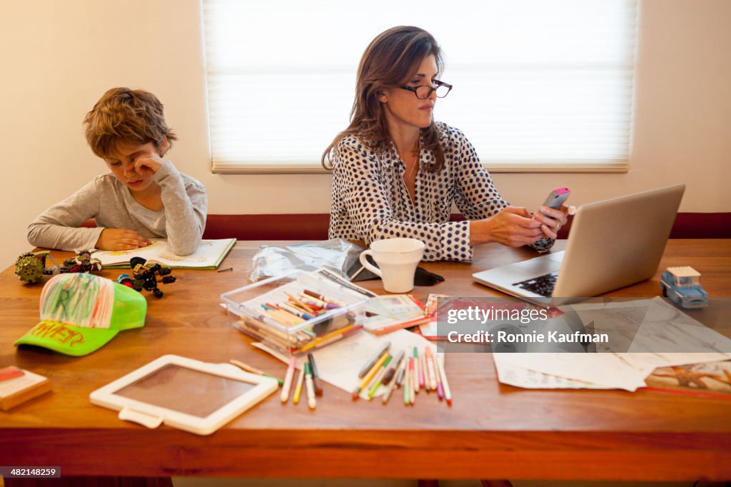 Caucasian mother and son working at table
