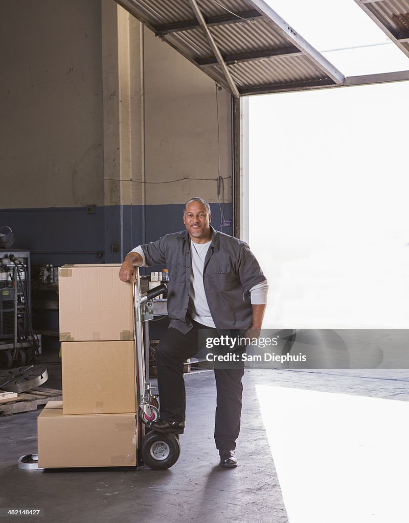 Worker with boxes on hand truck in warehouse