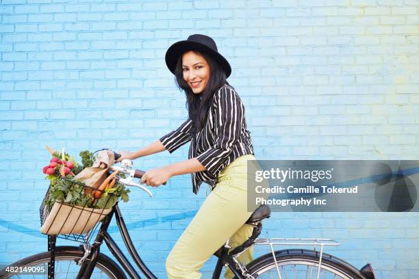 indian woman riding bicycle along brick wall - blue hat stock pictures, royalty-free photos & images