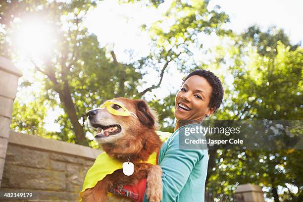 black woman carrying costumed dog in park - dog mask stock pictures, royalty-free photos & images