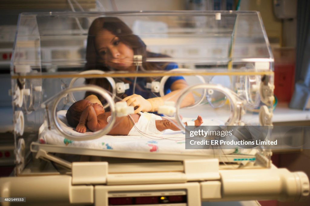 Nurse tending to newborn in incubator