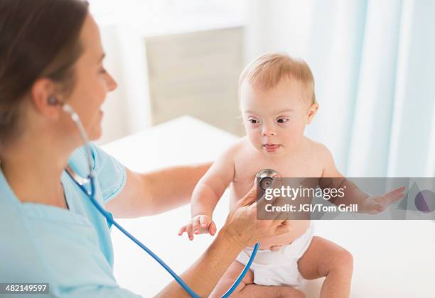 caucasian doctor tending to baby girl with down syndrome - down syndrome baby stockfoto's en -beelden