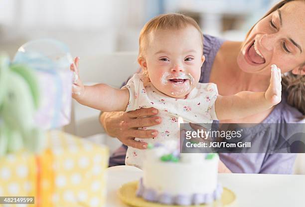 caucasian mother and baby girl with down syndrome celebrating birthday - down syndrome baby stockfoto's en -beelden