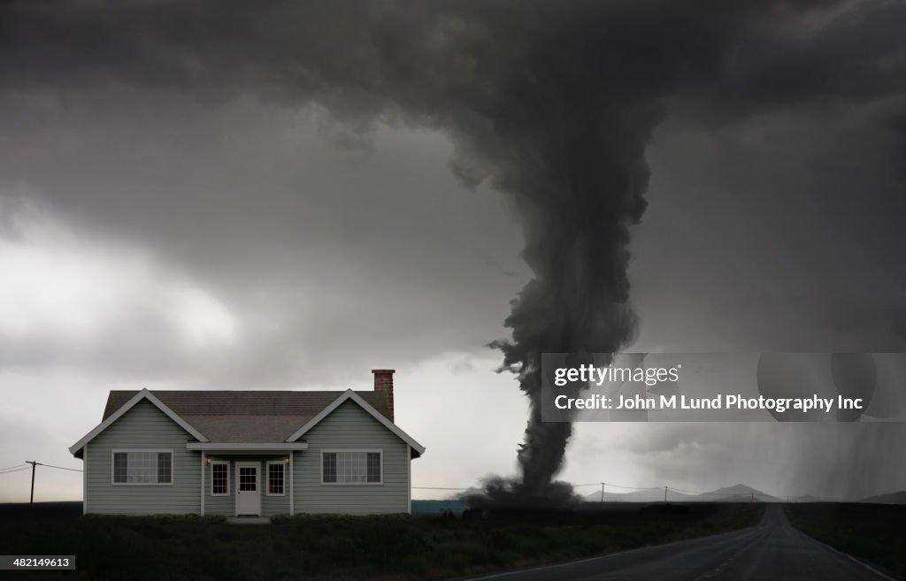 Tornado approaching house in rural landscape