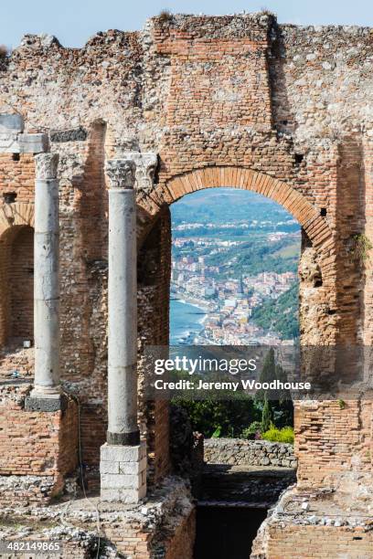 view through arch of ancient greek theatre ruins, taormina, sicily, italy - teatro greco taormina bildbanksfoton och bilder