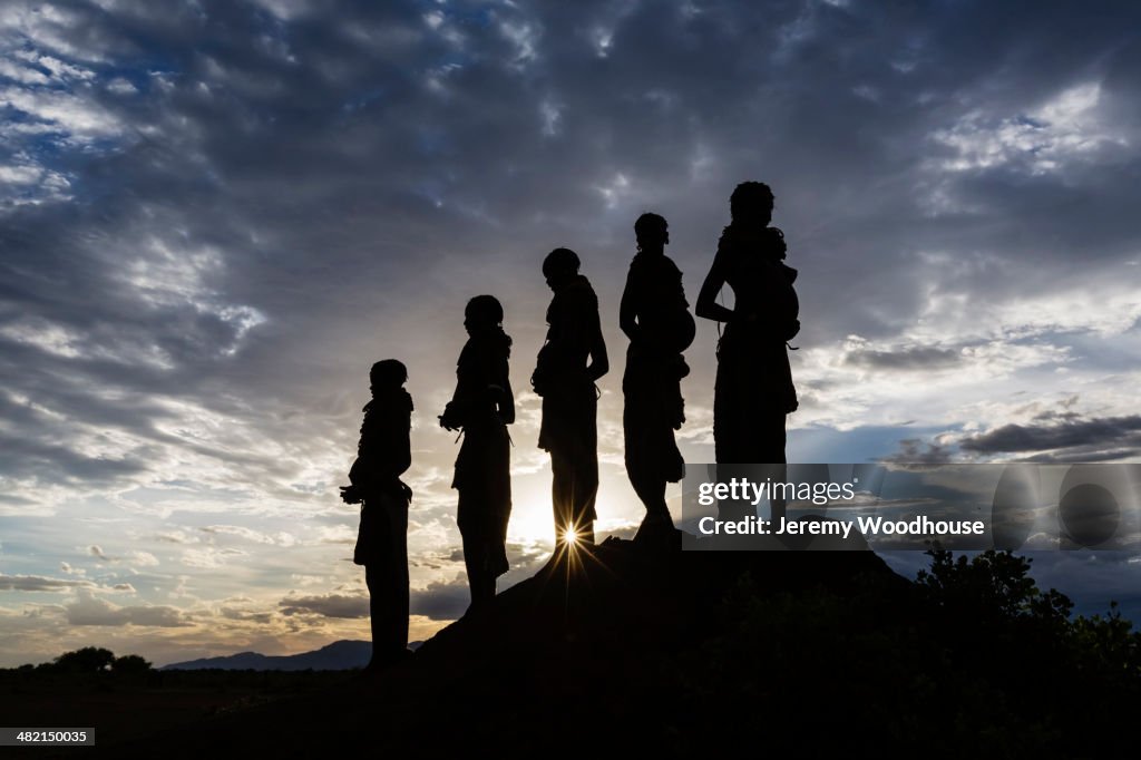Silhouettes of pregnant woman under cloudy sky at sunset, Nyangaton, Ethiopia