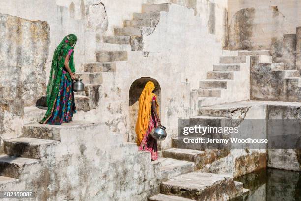 women in saris carrying water at step well, jaipur, rajasthan, india - stepwell india stock pictures, royalty-free photos & images