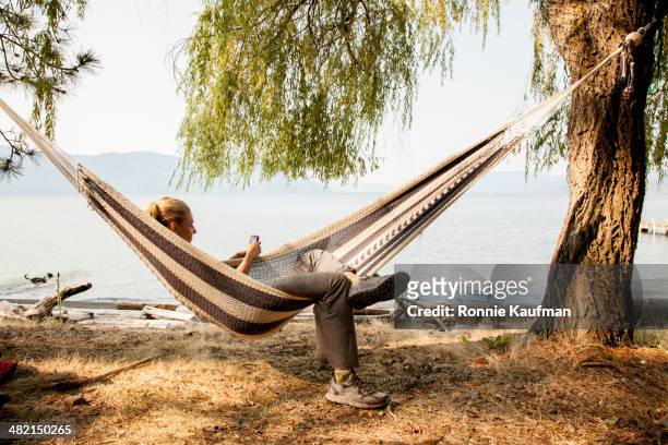 caucasian woman relaxing in hammock - hammock phone stock pictures, royalty-free photos & images