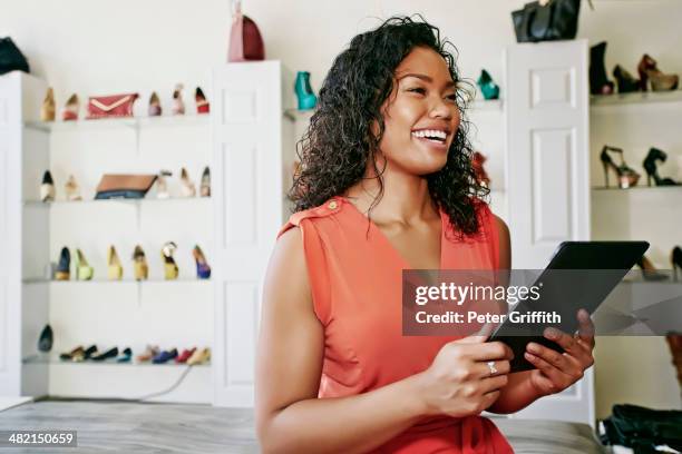 mixed race woman working in shoe store - black purse stockfoto's en -beelden