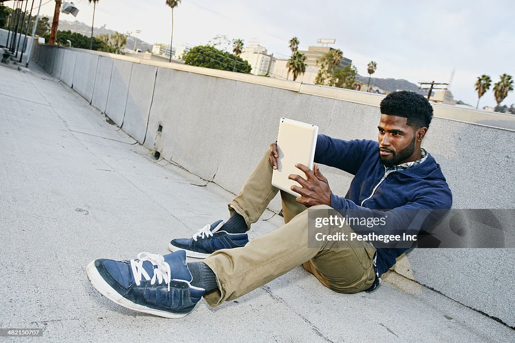 Black man using digital tablet on urban rooftop