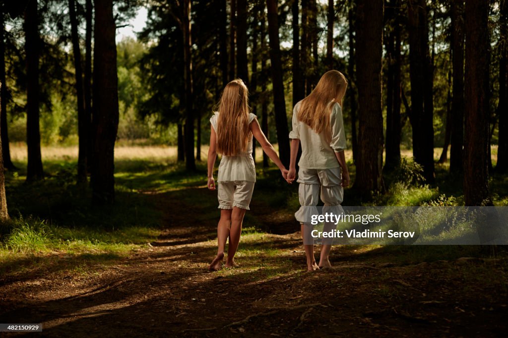 Caucasian girls holding hands in forest