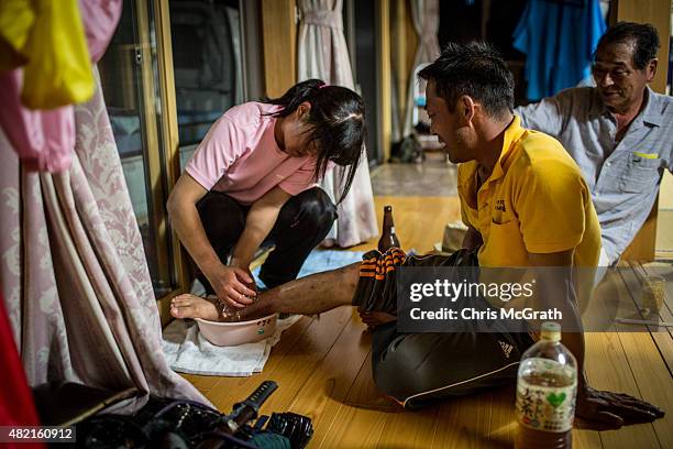 Ienobu Abe, a Samurai for 18 years has his ankle iced by his daughter Rina after the days racing at the Soma Nomaoi festival on July 26, 2015 in...