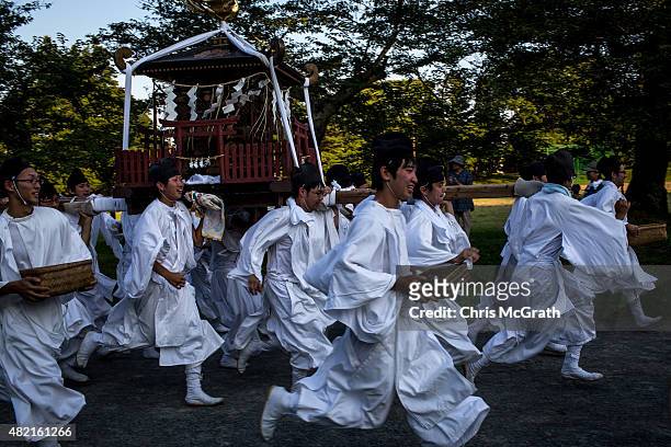 Young men carry a portable shrine to the Nakamura Shrine after the days racing during the Soma Nomaoi festival at Hibarigahara field on July 26, 2015...