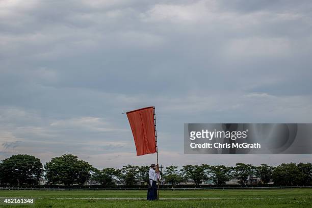 Man uses a flag to mark a starting point for a parade during the Soma Nomaoi festival at Hibarigahara field on July 25, 2015 in Minamisoma, Japan....