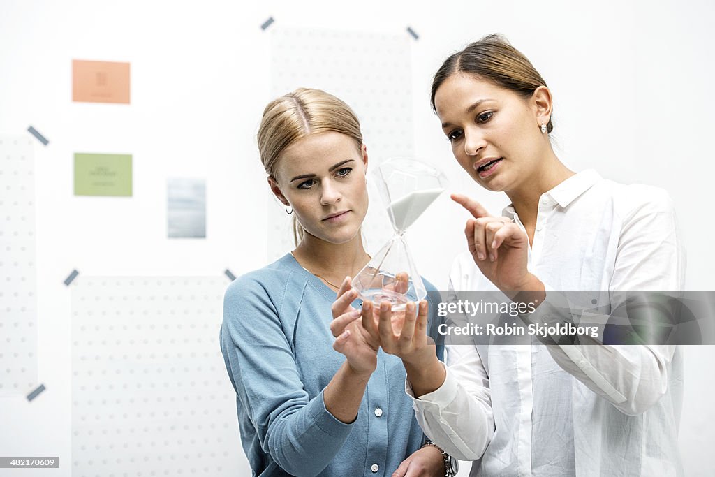 Female colleagues discussing workings of the hourglass