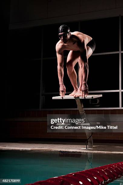 swimmer poised to dive into pool - diving platform pool stock pictures, royalty-free photos & images