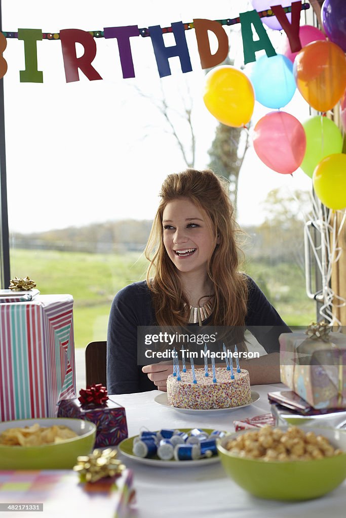 Teenage girl at  table with birthday cake